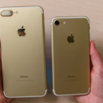 iPhone 7 og iPhone 7 Plus holdes op ved siden af hinanden med bagsiden opad. De er guld begge to og det ses tydeligt at iPhone 7 Plus til højre har den store brede kameralinse.