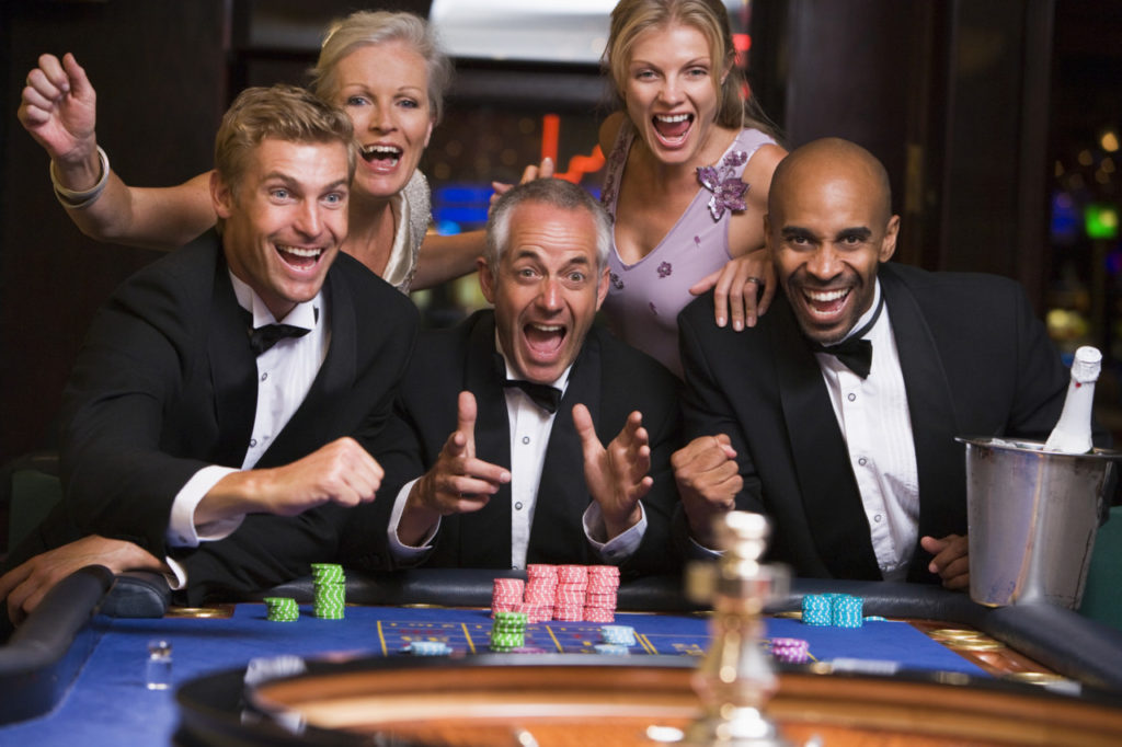 Entusiastiske festklædte mennesker spiller roulette på et casino